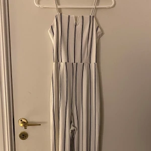 Vit och svart randig jumpsuit från Bershka - Säljer en superfin vit jumpsuit med svarta ränder från Bershka! Perfekt för sommardagar!🤗 Materialet känns lätt och bekvämt. Lite kort på mig som är 164cm😌