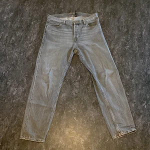 Grå jeansbyxor - Snygga grå jeansbyxor med klassisk femficksdesign och knappar. Perfekta för en avslappnad stil. De har en rak passform och är tillverkade i slitstarkt denim. Storlek 32/32