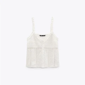 Vit spetslinne från Zara - Säljer ett vackert vitt spetslinne från Zara med smala axelband och v-ringning. Linnet har fina spetsdetaljer och en lätt ribbad struktur. Perfekt för en somrig look!