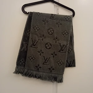 Grå halsduk - Elegant grå halsduk med ikoniskt mönster. Tillverkad i en lyxig blandning av silke och ull, vilket ger en mjuk och varm känsla. Perfekt för att lyfta vilken outfit som helst med en touch av exklusivitet.