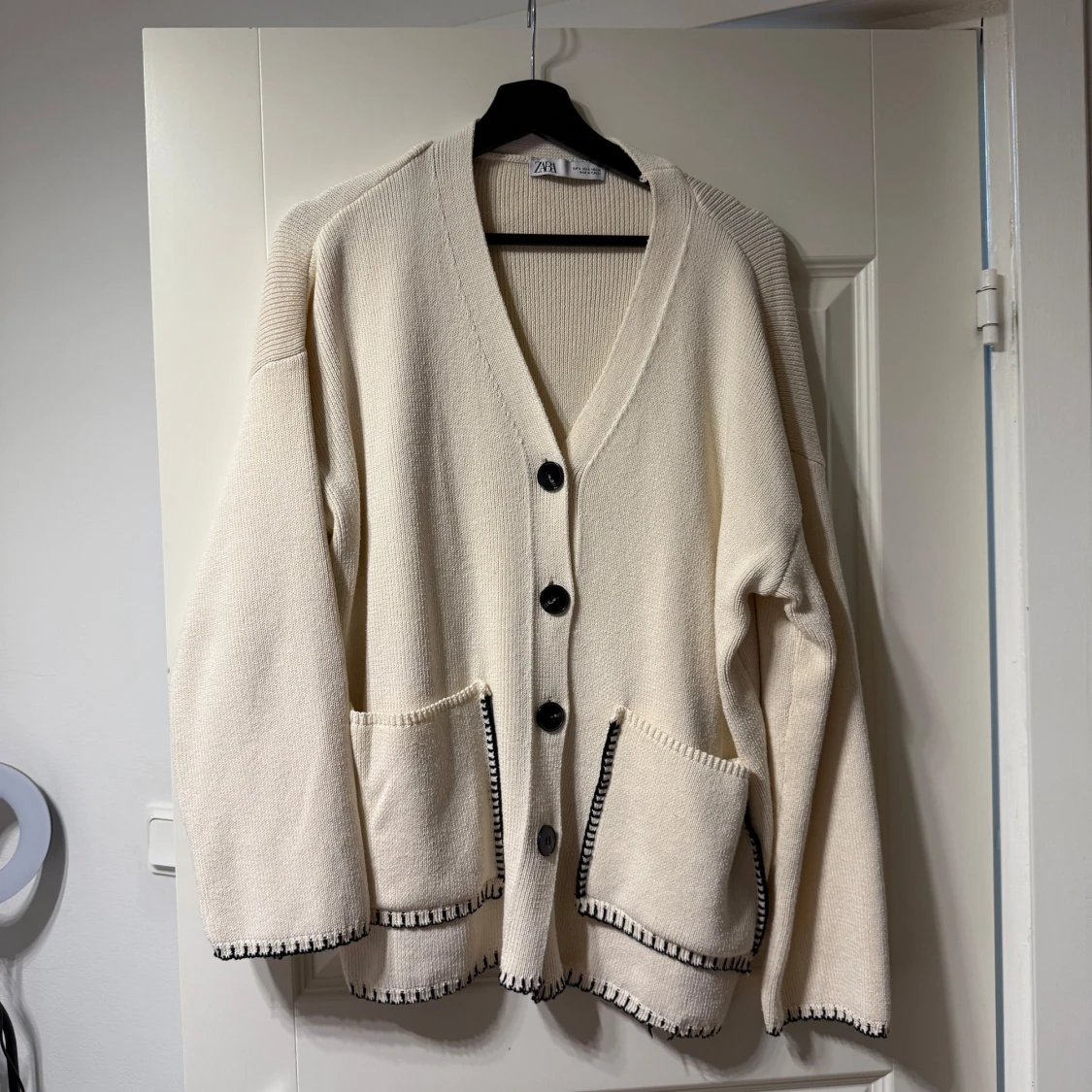 Beige kofta med svarta knappar