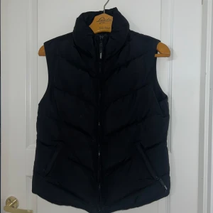 Svart dunväst med dragkedja - Säljer en stilren svart väst, använd fåtal gånger, storlek M men passar även S