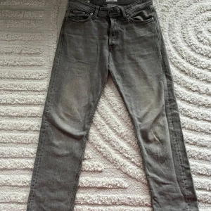 Grå jeans från Jack & Jones - Säljer ett par grå jeans från Jack & Jones med en relaxed fit. Modellen heter Chris och har en klassisk femficksdesign. Perfekta för en avslappnad stil. Storleken är 29/32.
