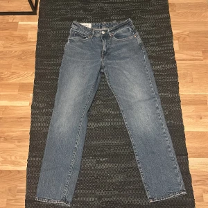 Blå jeans från H&M - Säljer ett par klassiska blå jeans från H&M i straight regular fit. De har en midwaist och är perfekta för en avslappnad. Jeansen är i storlek 28/32