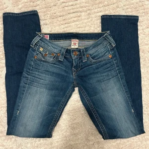 Blå jeans från True Religion - Snygga blå jeans från True Religion med klassisk femficksdesign och kontrastsömmar. Jeansen har en låg midja och bootcut-stil! Älskar dem, men jeansen är för små på mig❤️ 