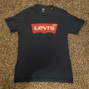 Svart t-shirt från Levi's - Snygg svart t-shirt från Levi's med det klassiska röda logotyptrycket på bröstet. Perfekt för en avslappnad stil. Tillverkad i mjuk bomull för extra komfort.
