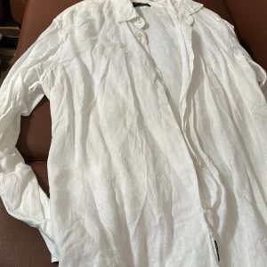 Vit linneskjorta från Sand Copenhagen - Snygg vit skjorta i linne från Sand Copenhagen. Perfekt för en stilren look med sina långa ärmar och klassiska knappar. Modern fit som ger en bekväm passform. Ett måste i garderoben för en fräsch och luftig stil.