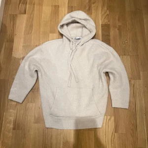 Beige stickad hoodie från Zara - Mysig beige stickad hoodie från Zara med en stor huva. Perfekt för kyliga dagar med sin mjuka och bekväma passform. Den har långa ärmar och en praktisk ficka framtill. Riktigt fint skick och gött material. S men sitter mer som M