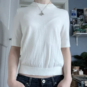 Vit stickad tshirt ny utan prislapp - Säljer en stilren vit tröja med korta ärmar. Perfekt för en minimalistisk look. Tröjan har en rund halsringning och är gjord i ett mjukt material som ger en bekväm passform.
