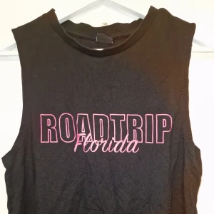 Svart  topp från Gina Tricot - Snygg svart topp från Gina Tricot med rosa text på framsidan. Perfekt för träning eller till sommaren. Garderobsrensning så kika gärna på övriga auktioner.