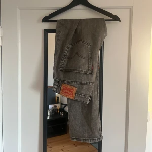 Grå Levis jeans - Snygga grå Levis jeans med klassisk design. De har en rak passform och är perfekta för en avslappnad stil. Märkeslappen och den ikoniska röda etiketten ger en autentisk look.