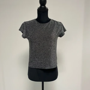 Glittrig fest-topp - Glittrig topp från Kappahl, är i stl 146/152 (barn) men har används som en croppad t shirt för stl XXS/XS🪩🖤✨