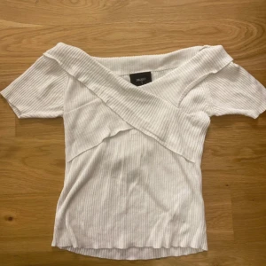 Vit ribbad topp från Object - Snygg vit ribbad topp från Object med korta ärmar och omlott-design. Perfekt för en stilren look.