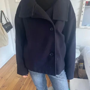 Marinblå kappa med stora knappar - Snygg  kappa med stora knappar framtill och en bred krage. Jackan har en stilren design och långa ärmar, perfekt för kyligare dagar. Passar bra till jeans eller klänning. Barnstorlek 170 men passar mig lagom som har S