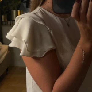 Vit blus med volangärmar - Vit blus med korta volangärmar. Säljer pga att den ej kommer till användning 🤍vet ej vart den är från eller storlek då jag ärvt den, men den sitter som en s.