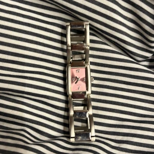 Silverfärgad klocka med rosa urtavla - Elegant klocka med en rektangulär rosa urtavla och silverfärgad länkarmband. Batteriet är helt nytt, det går att ta bort länkar men det är inte lätt🥲