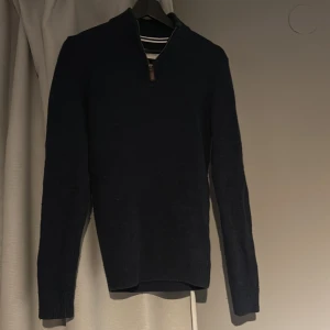 Mörkblå stickad tröja från Pier One - Säljer en stilren mörkblå stickad tröja från Pier One. Tröjan har en dragkedja vid halsen och ribbade detaljer vid kragen. Perfekt för kyligare dagar. 9/10 skick