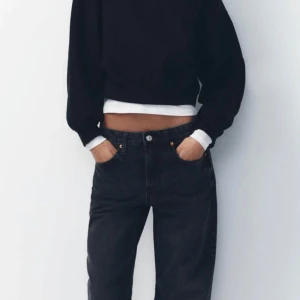 Svarta jeans mid waist - Snygga svarta jeans med hög midja och en avslappnad passform. De har en klassisk design med fem fickor och knappgylf. Perfekta för en stilren look.