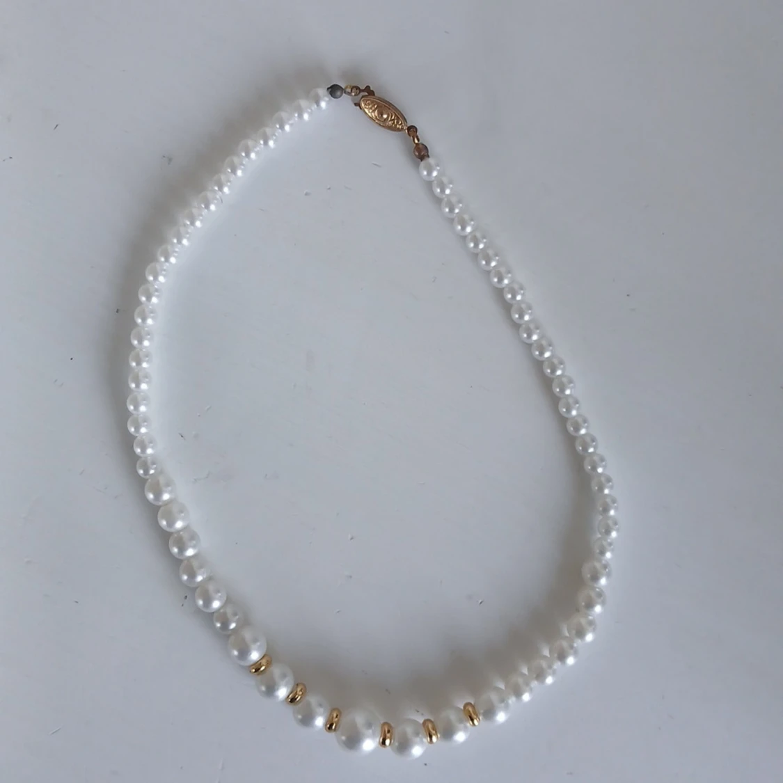 Vitt pärlhalsband med gulddetaljer