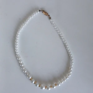 Vitt pärlhalsband med gulddetaljer - Elegant vitt pärlhalsband med små gulddetaljer och ett dekorativt guldfärgat lås. Perfekt för att ge en klassisk touch till din outfit. Ej justerbar med ett gammaldags lås. 