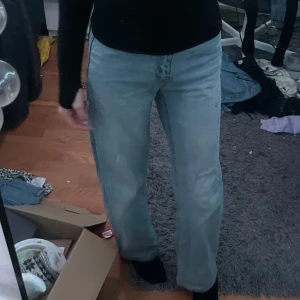 Ljusblå jeans - Säljer ett par ljusblå jeans med en avslappnad passform. De har en klassisk design med fem fickor och knappgylf. Perfekta för en casual look.