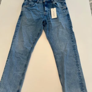 Blå jeansbyxor från G-Star RAW - Snygga blå jeansbyxor från G-Star RAW i en klassisk straight fit. Byxorna har en midwaist och är tillverkade i slitstarkt denim. Perfekta för en avslappnad stil med en touch av trend. De har en dragkedja och knappar framtill.
