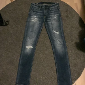 Blå slim fit jeans - Snygga blå slim fit jeans från Jack & Jones med leopard slitna detaljer och en naturlig fade. Med bra denim och en slim fit passform blir dom perfekta. storlek 29/34 men sitter mer som 32 i längden. Nypris är runt 700 men mitt pris är 350 ( Självklart är de diskuterbart) Hör av er vid frågor 
