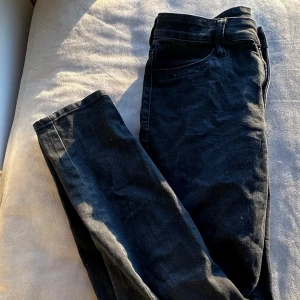 Svarta skinny jeans - Snygga svarta skinny jeans med regular waist och ankellängd. Perfekta för en stilren look. Tillverkade i denim.