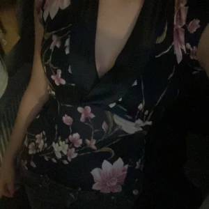 Svart blommig omlottopp - Säljer eftersom den inte kommer till andvändning! Men är väldigt fin! Och bra skick. Med knyte där bak❣️