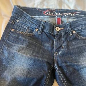 Mörkblå jeans från Esprit - Snygga mörkblå jeans från Esprit med en klassisk femficksdesign. De har en rak passform och är perfekta för en avslappnad stil. Jeansen har en knappgylf och subtila slitningar för en trendig look.