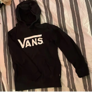 Svart hoodie från Vans - Säljer en svart hoodie från Vans med deras ikoniska logga i vitt på bröstet. Perfekt för en avslappnad stil med en skön passform och huva. Passar bra till både jeans och joggers. (Första bilden är lånad)