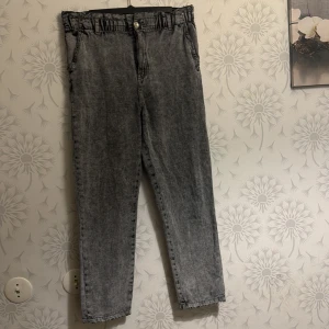 Grå jeans med resårmidja - Snygga grå jeans med en bekväm resårmidja och knappstängning. De har en rak passform och är perfekta för en avslappnad stil. Jeansen har en klassisk design med fickor fram och bak.