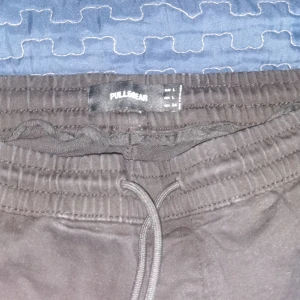 Svarta byxor från Pull&Bear - Snygga svarta byxor från Pull&Bear med elastisk midja och snörning. Perfekta för en avslappnad stil.