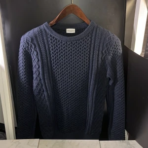 Mörkblå stickad tröja från John Henric - Säljer en snygg mörkblå stickad tröja från John Henric. Tröjan har ett speciellt flätmönster och rund halsringning. Perfekt för kyliga dagar och för att sticka ut i mängden, hör av er vid minsta fundering🙌