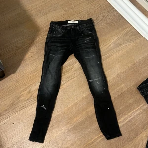 Svarta jeans från Replay - Snygga svarta Replay jeans med en slim passform och slitna detaljer. Perfekta för en trendig look. De har en klassisk femficksdesign och en bekväm midja.