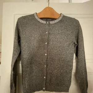 Kofta med glitterdetaljer - Säljer en jättefin grå kofta med glitterdetaljer runt halsen. Perfekt för en lite extra fin detalj i vardagen! Ser jättefin ut och den har inga defekter. Nypris: 300. Säljer för 200 men pris kan såklart diskuteras 🫶