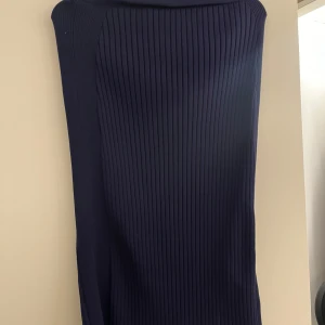 Mörkblå ribbad midikjol från ONLY - Snygg mörkblå ribbad kjol från ONLY. Perfekt för en stilren look med sin enkla design och bekväma passform. Kjolen är i en mörk nyans och har en ribbad struktur som ger en modern touch.