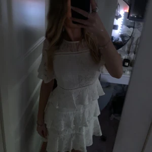 Vit spetsklänning med volanger från bubbleroom - Charmig vit spetsklänning med volanger och kort ärm från Bubbleroom. Klänningen har en rund hals och en dragkedja i ryggen. Perfekt som studentklänning, midsommar klänning eller andra sommar festligheter. Har använts en gång!😍pris kan diskuteras vid snabb affär🫶🏻
