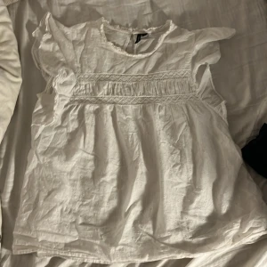 Stockholmsstil Vit blus från Vero Moda - Säljer en söt vit  trendig blus från Vero Moda med volangdetaljer och spets! Funkar i alla lägen. Säljer då den är för stor!