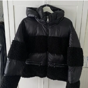 Svart pufferjacka med teddy-detaljer - Snygg svart pufferjacka med teddy-detaljer som passar så bra nu på vintern, har haft den förra säsongen men tyvärr kommer den ej till användning längre💕så unik och snygg!!skriv för fler bilder eller vid frågor, inga defekter!