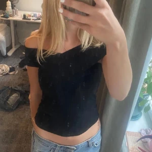 Svart offshoulder topp - Snygg svart offshoulder topp som passar perfekt till både jeans och kjol. Den har en tight passform och är tillverkad i ett mjukt material som sitter skönt mot huden. 