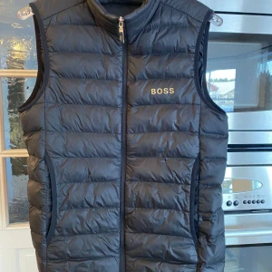 Hugo Boss väst - Säljer denna Hugo Boss västen i storlek XS då den inte kommer till användning längre. Finns ett litet brännhål på framsidan som knappt syns, annars i mycket bra skick! 