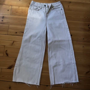 Vita jeansbyxor från BDG Urban Outfitters - Säljer mina favvo jeansbyxor från BDG Urban Outfitters med en loose passform och hög midja. Byxorna har råa kanter vid bensluten för en trendig look. Väldigt bra kvalitet och ser knappt använda ut. Ursprungspris: 1000kr.
