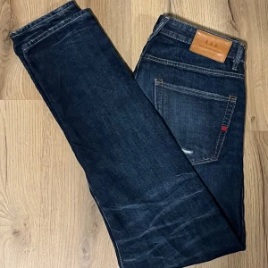 Jack and Jones jeans - Snygga jeans från Jack & Jones Royal Denim Division. Mörkblå denim med klassisk femficksdesign och knappgylf. Perfekta för en avslappnad stil. Slim/Straight 