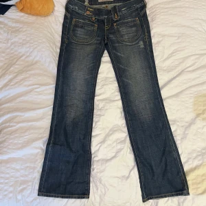 Fina lågmidjade bootcut jeans med söta blommdetaljer - Så fina lågmidjade bootcut jeans med söta broderade blommdetaljer. Unika och mycket fina. Står inte pris men de passar mig som prylar ha strl 34 i byxor. 