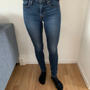 Blå jeans från Levi's - Snygga blå jeans från Levi's med hög midja och skinny passform. Klassisk femficksdesign med dragkedja och knapp framtill. Perfekta för en stilren look. Frakt tillkommer fr 50kr