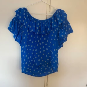 Blå prickig blus från Yves Saint Laurent - Supersöt blå blus med prickar från Saint Laurent! Kan bäras som off-shoulder och ”vanligt”. Mycket bra skick och perfekt nu till våren!🥰🥰