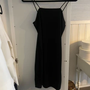 Svart klänning från Bik Bok - Elegant svart klänning från Bik Bok med smala axelband. Perfekt för en stilren look. Klänningen har en enkel och tidlös design som passar många tillfällen.