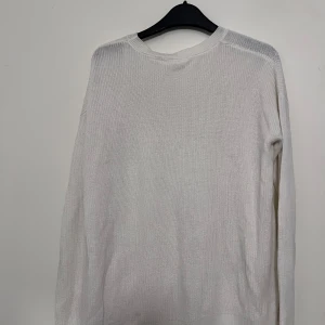 Vit stickad tröja - Säljer en stilren vit stickad tröja med rund halsringning. Tröjan har långa ärmar och en mjuk textur, perfekt för kyligare dagar. Passar bra till både jeans och kjol.