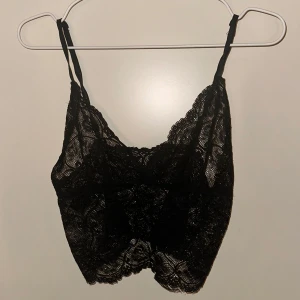 Svart spetslinne - Snyggt svart spetslinne med tunna axelband och vacker spetsdesign. Perfekt för att lägga till en touch av elegans till din outfit.
